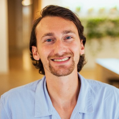 Zack Kadish, senior SEO strategy director for Conductor, smiles in a blue collared shirt in front of a blurred office background. 