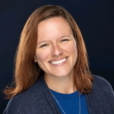 Mariah Tang, assistant vice president of content marketing at Stamats, smiles in a blue top against a dark background. 