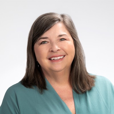 Michelle Garret, consultant and writer for Garrett Public Relations, smiles in a green shirt against a pale background. 