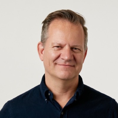 Michael Bonfils, global managing director at Digital International Group, smiles in a black shirt in front of a pale background. 