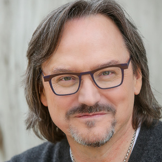 Robert Rose is wearing glasses and has brown hair and a goatee. 